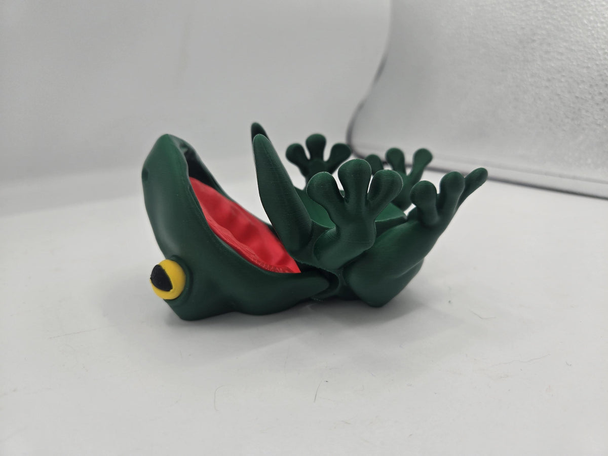 Frog Can Cover 3D print lying on its side with mouth wide open, red mouth interior and articulated hinged jaw visible, green PLA