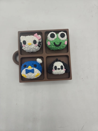 Sanrio themed rice ball tray clicker fidget from above — kitty, frog, penguin, and puppy rice balls in a brown bento-style tray with keychain loop, 3D printed