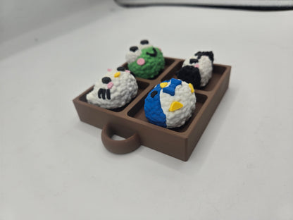 Angled view of the Sanrio themed rice ball tray clicker fidget showing the tray depth and keychain loop, four rice ball characters, 3D printed