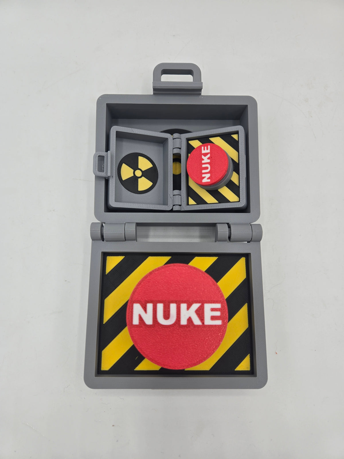 Top Secret Briefcase Nuclear Mechanical Key Fidget Clicker 3D print open on desk with mini keychain version nested inside — red NUKE button on yellow-black hazard stripes, radiation symbol lid