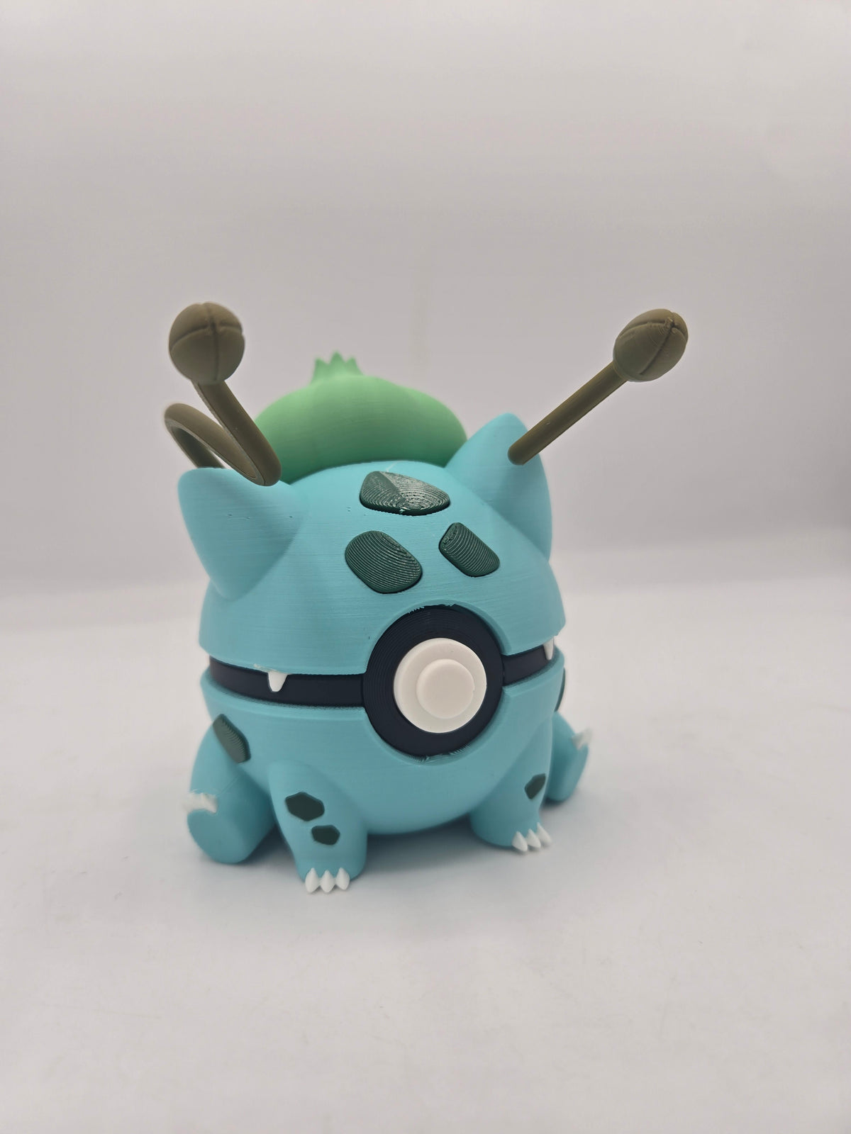 Pokémon Pokéball Inspired Clickers 3D print — Bulbasaur style clicker, teal shell with green spots, bulb and sprouting stalks on its back
