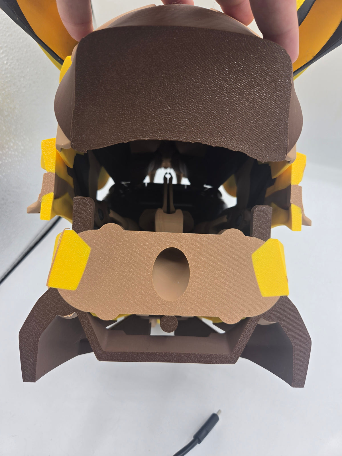 Mekachu Mecha Monster controller holder 3D print held from above showing the rear charging cord hole in the back panel and base legs, USB-C cable beside it