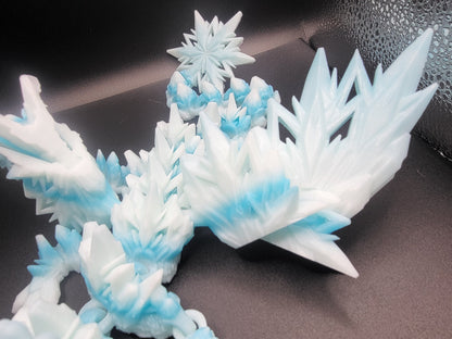 Detail of the Baby Winter Dragon's crystal-spike wings with a small snowflake perched above — 3D printed with a frost-blue gradient