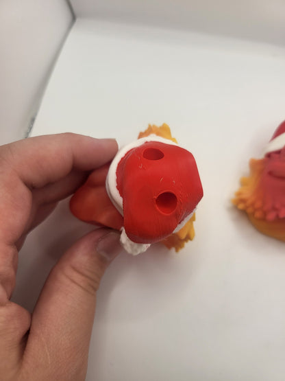 Back of the magnet version of the Bearded Dragon with Santa Hat held in a hand, showing the two recessed magnet holes — 3D printed ornament or magnet
