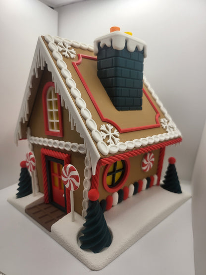 Holiday Gingerbread House Display, 3D printed — angled view on a snowy base with icing-trimmed roof, snow-capped chimney, peppermint lollipops, and spiral pine trees