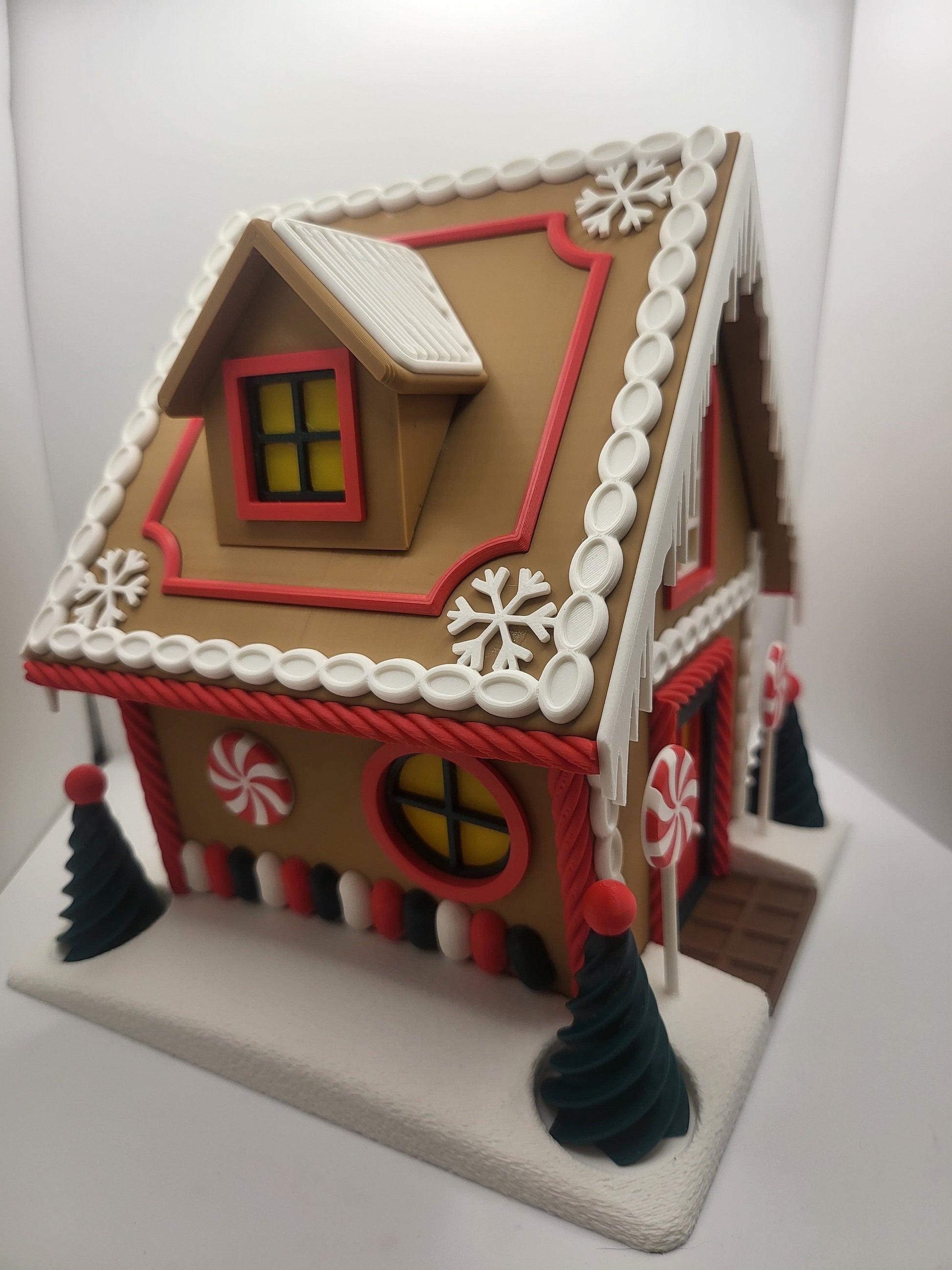 Holiday Gingerbread House Display, rear corner view — round candy window, dormer, gumdrop trim, and snowflake roof accents, 3D printed