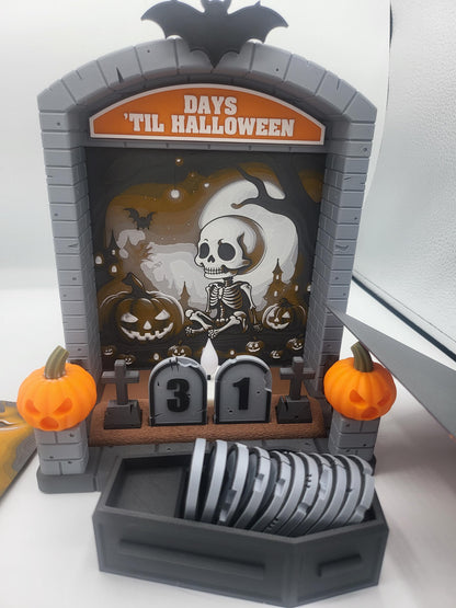 Halloween Countdown with skeleton graveyard backdrop in daylight — coffin storage filled with tombstone-shaped numbers in front of the display, 3D printed