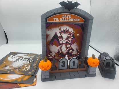 Halloween Countdown with playful dragon backdrop in bright light — coffin storage box beside the display and extra backdrops stacked at left, 3D printed