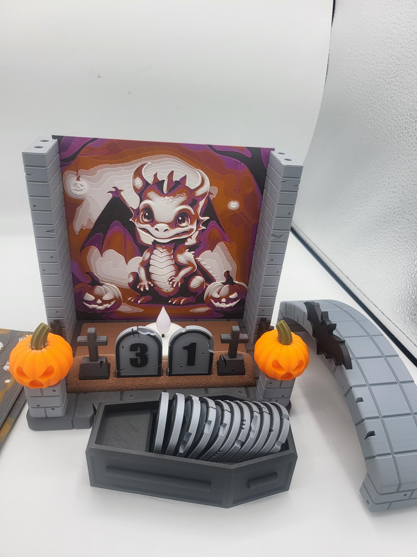 Halloween Countdown partially disassembled — dragon backdrop panel with the arch removed, showing how backdrops swap in and out, coffin of tombstone numbers in front