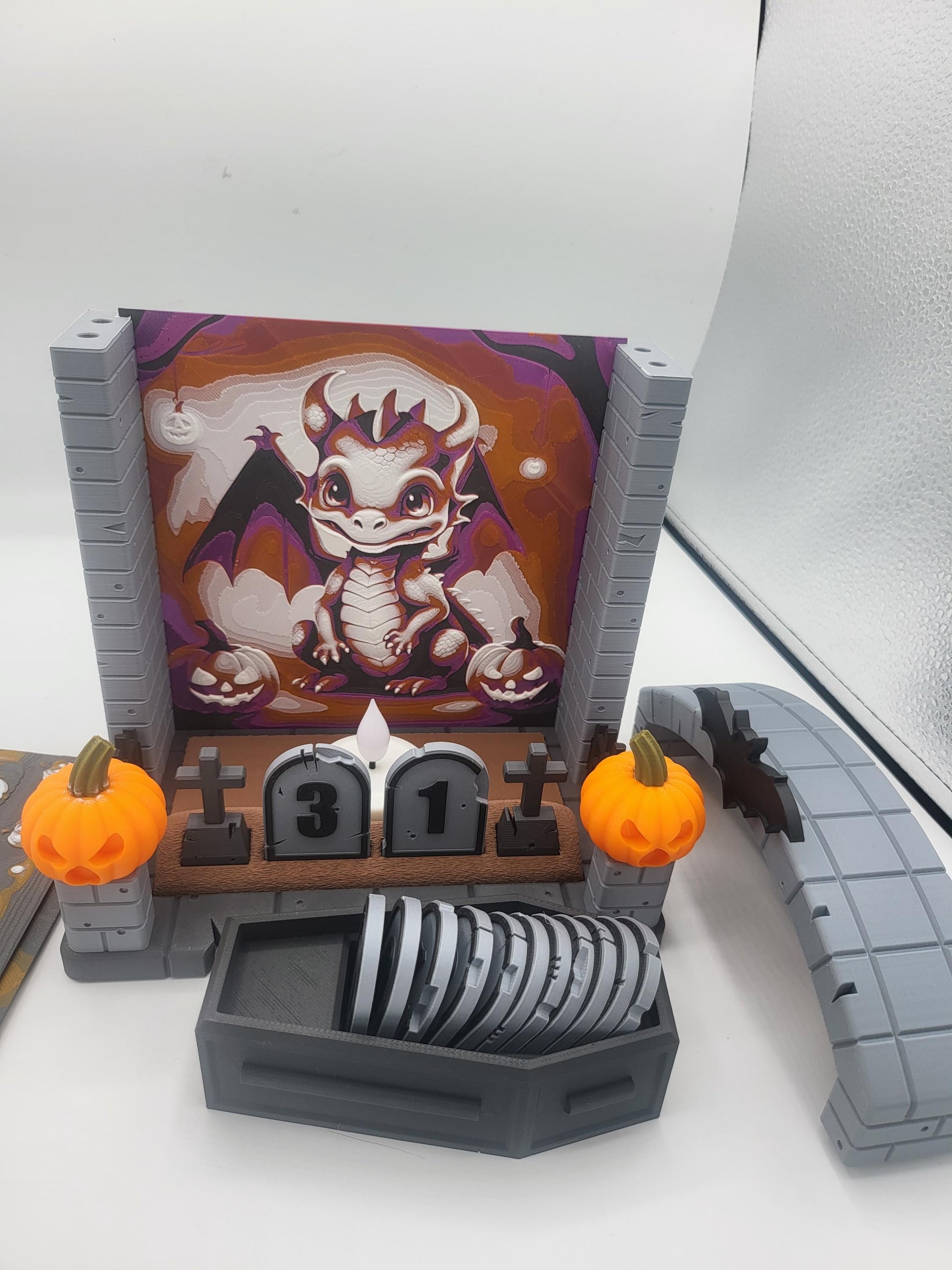 Halloween Countdown partially disassembled — dragon backdrop panel with the arch removed, showing how backdrops swap in and out, coffin of tombstone numbers in front