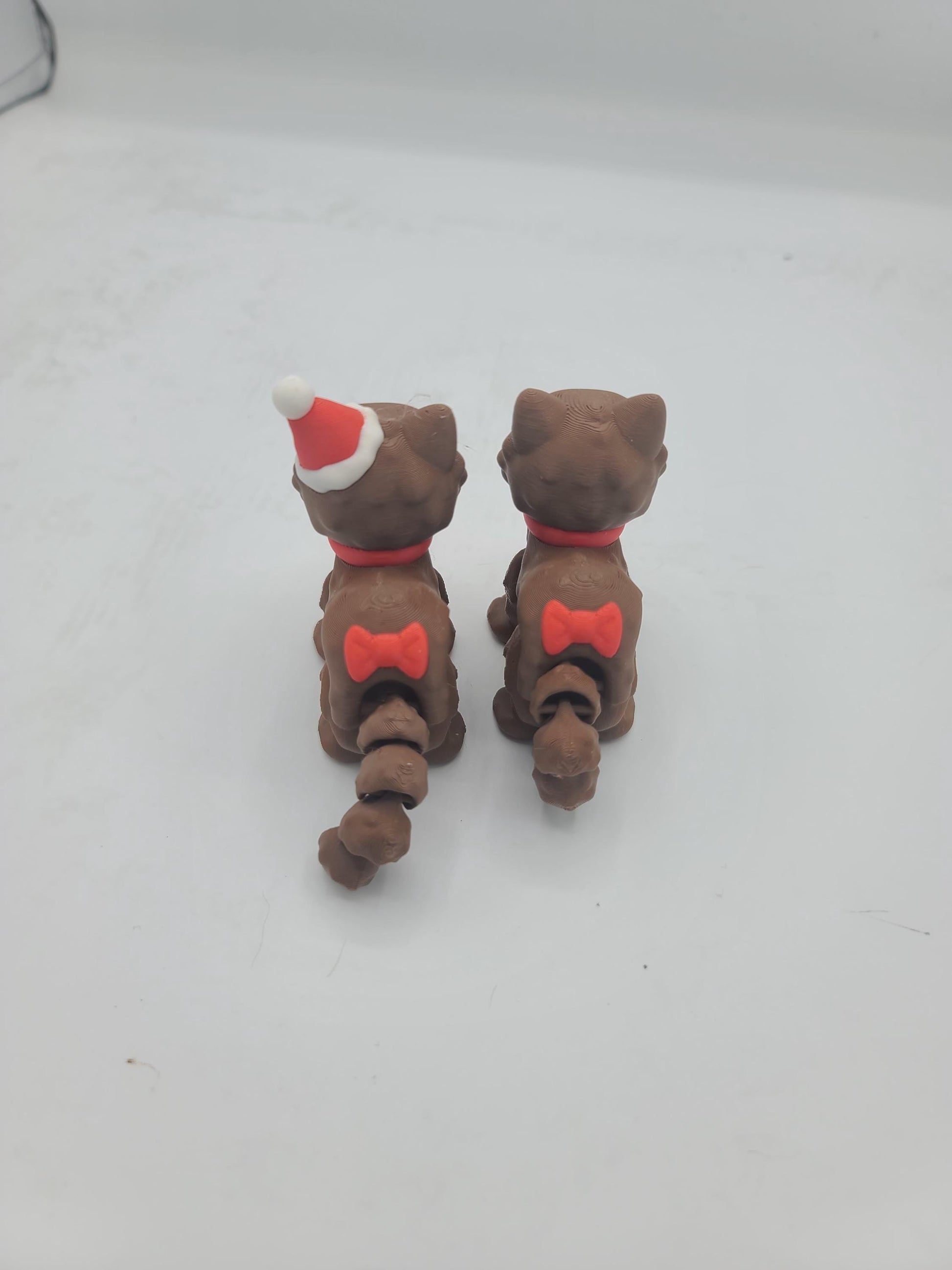 Back view of both Cocoa Kitty styles showing the cute red bows on their articulated tails — holiday flexi cats, 3D printed