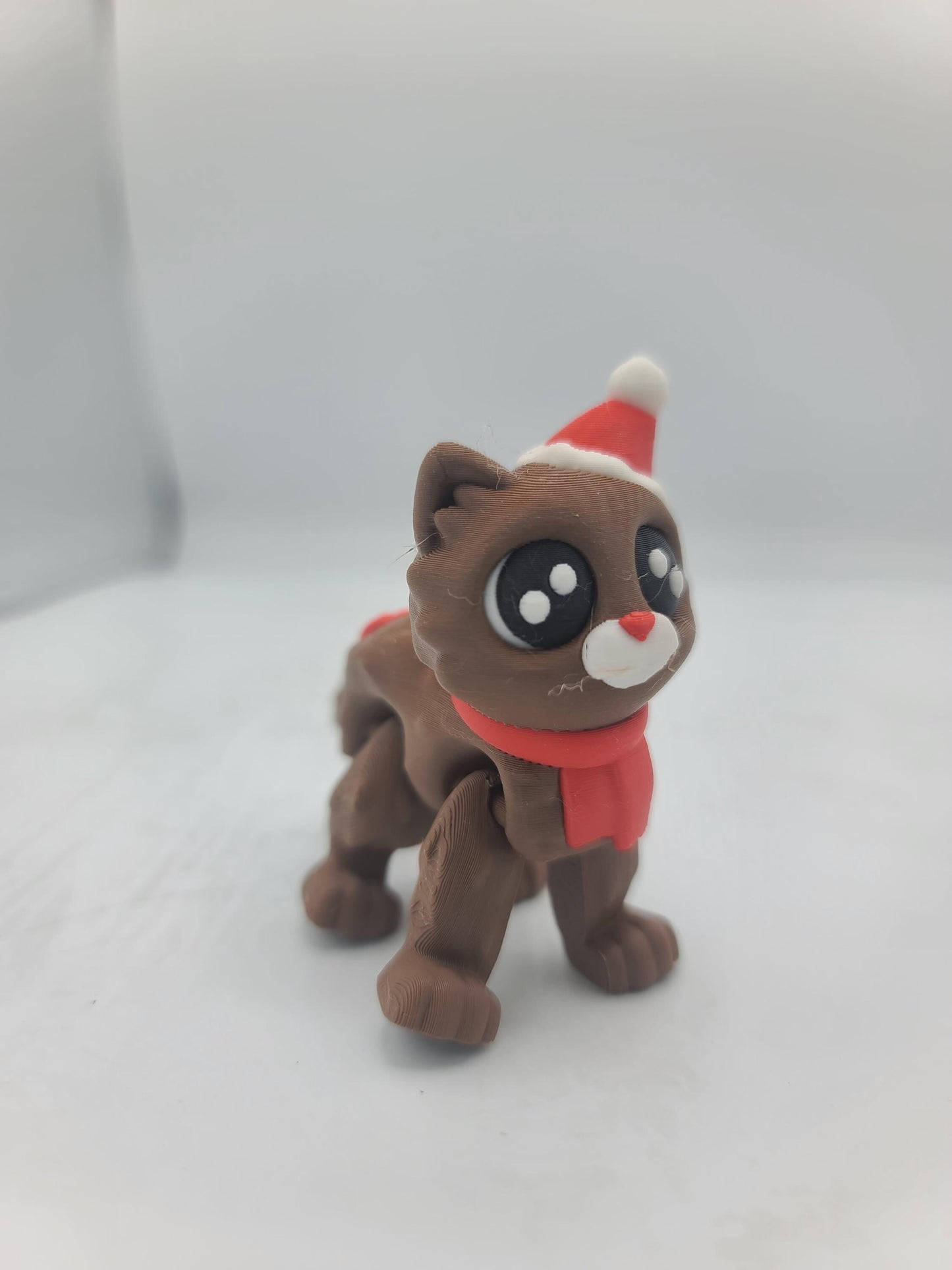 Cocoa Kitty in the Santa Hat style standing alone — brown 3D printed flexi cat with red scarf, white muzzle, and Santa hat