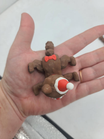 Cocoa Kitty flexi cat resting in the palm of a hand for scale, showing the red tail bow and articulated joints — 3D printed holiday cat