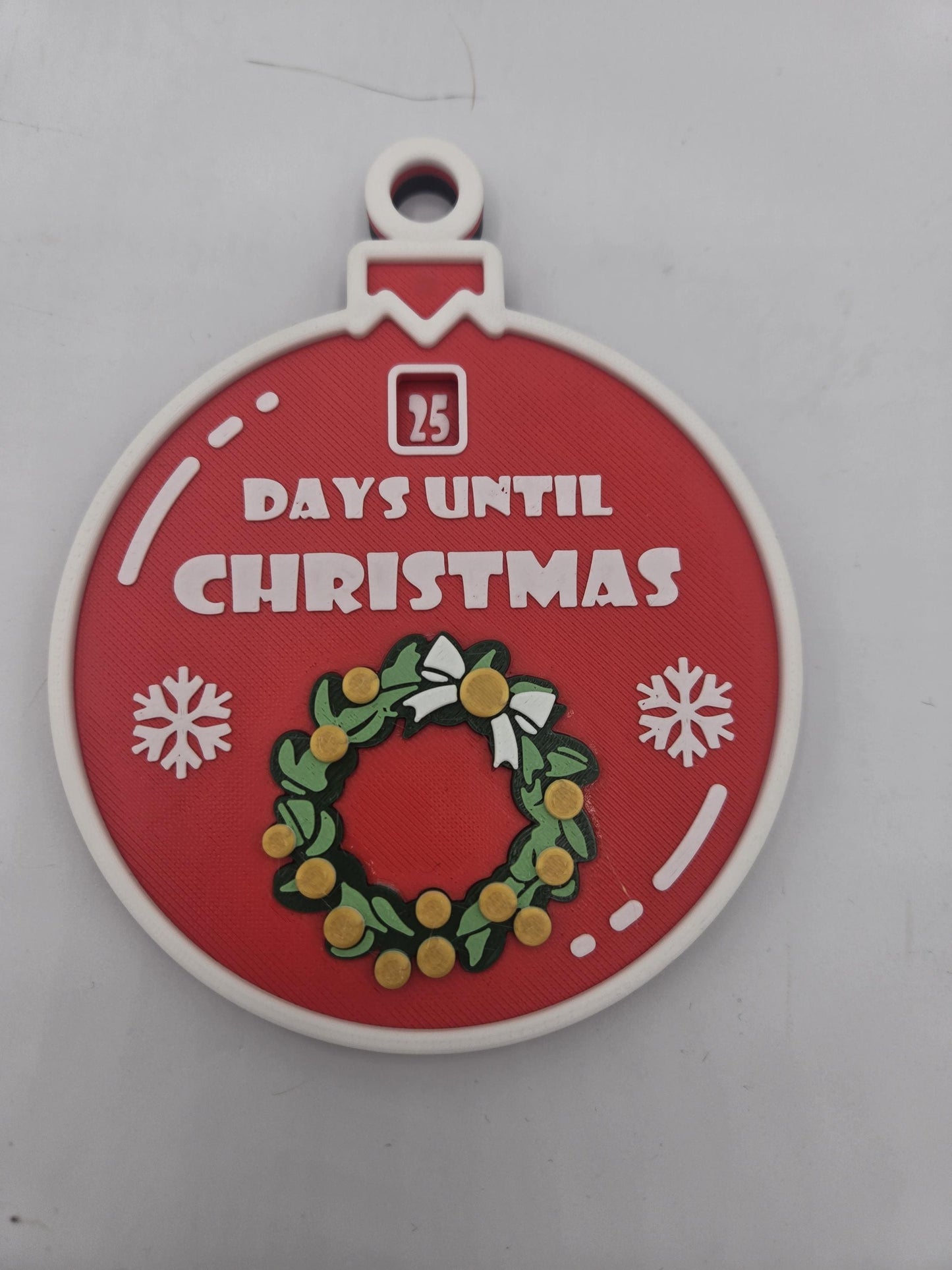 Angled close-up of the 3D printed Christmas 25 Day Countdown ornament — layered wreath, bow, and snowflake detailing around the countdown window