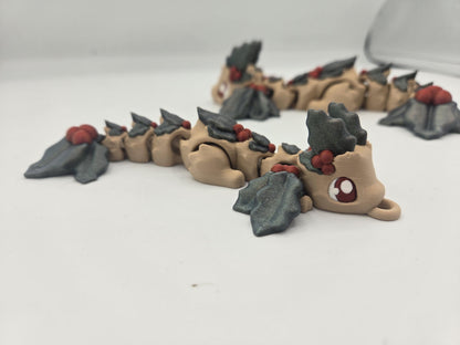 Mistletoe Dragon flexi side view lying flat, showing articulated body segments, holly leaf wings, and keychain loop — 3D printed