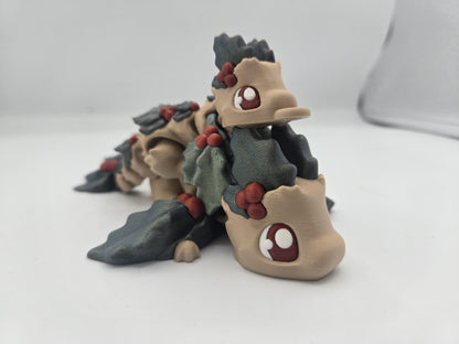 Mistletoe Dragon flexi close-up — beige 3D printed dragons with dark holly leaves, red berries, and big red-and-white cartoon eyes