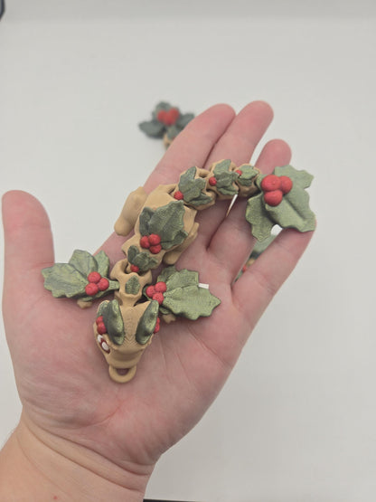 Keychain sized Mistletoe Dragon flexi held in a hand for scale — 3D printed with green holly leaves and red berries