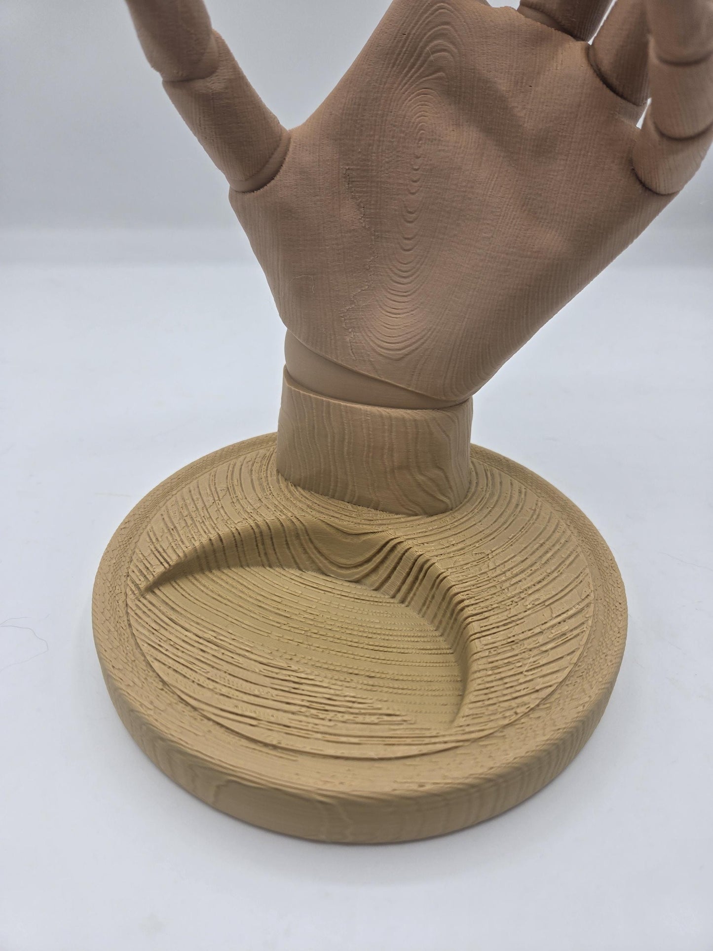 Close-up of the wood-grain textured round base and wrist of the hand-shaped wine bottle holder