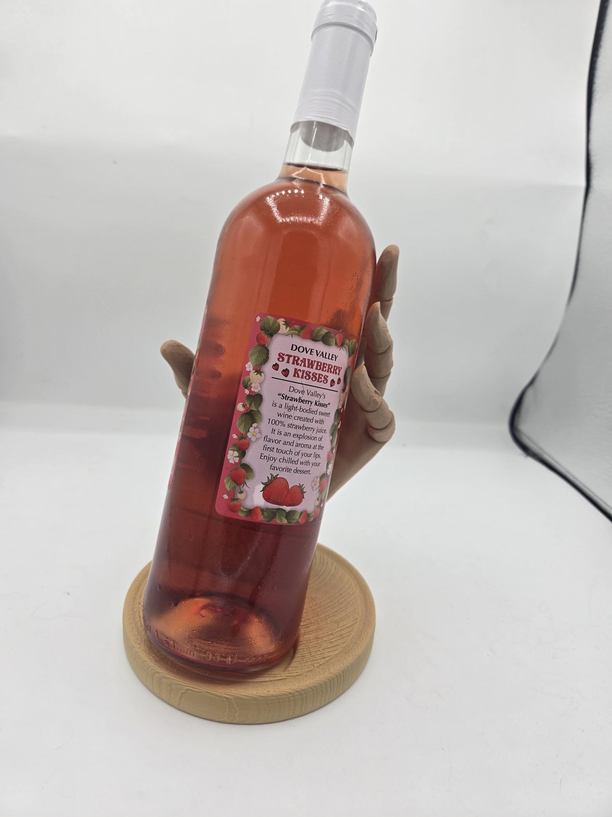 Front view of a rosé wine bottle resting in the 3D printed wooden hand display holder