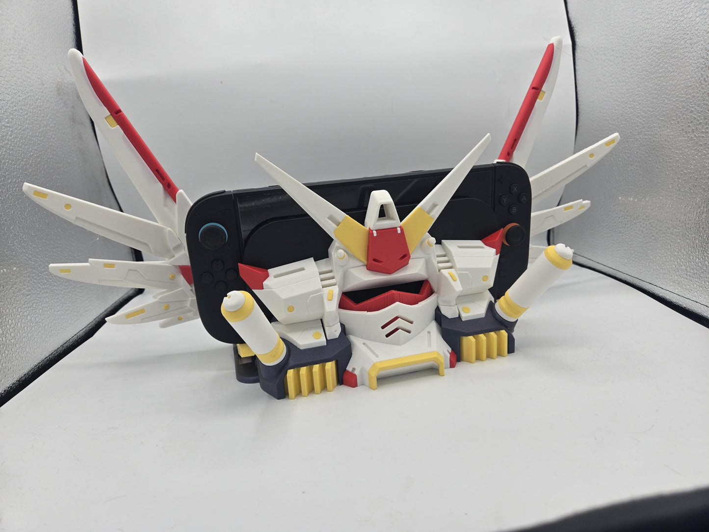 Mechdam Nintendo Switch 2 Dock Display in full anime launch pose — wings raised around the docked console, 3D printed in white, red, and yellow