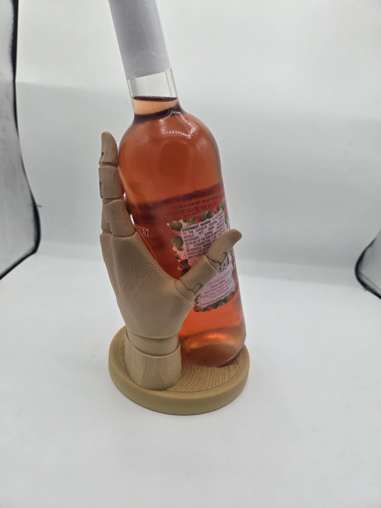 Back view of the sculpted hand cradling a full wine bottle upright on its round base