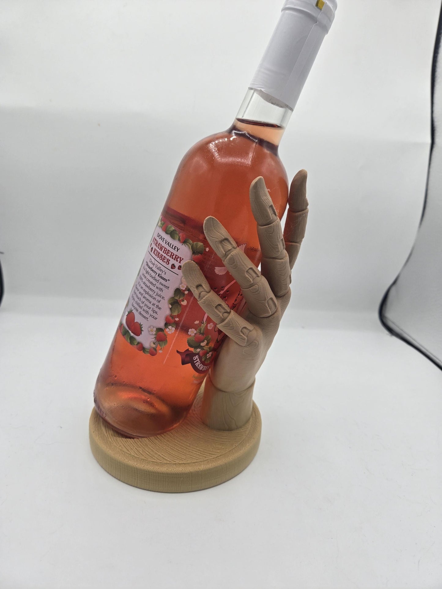 Wooden hand holder displaying a wine bottle at an angle — fingers wrapping the bottle for a floating held look