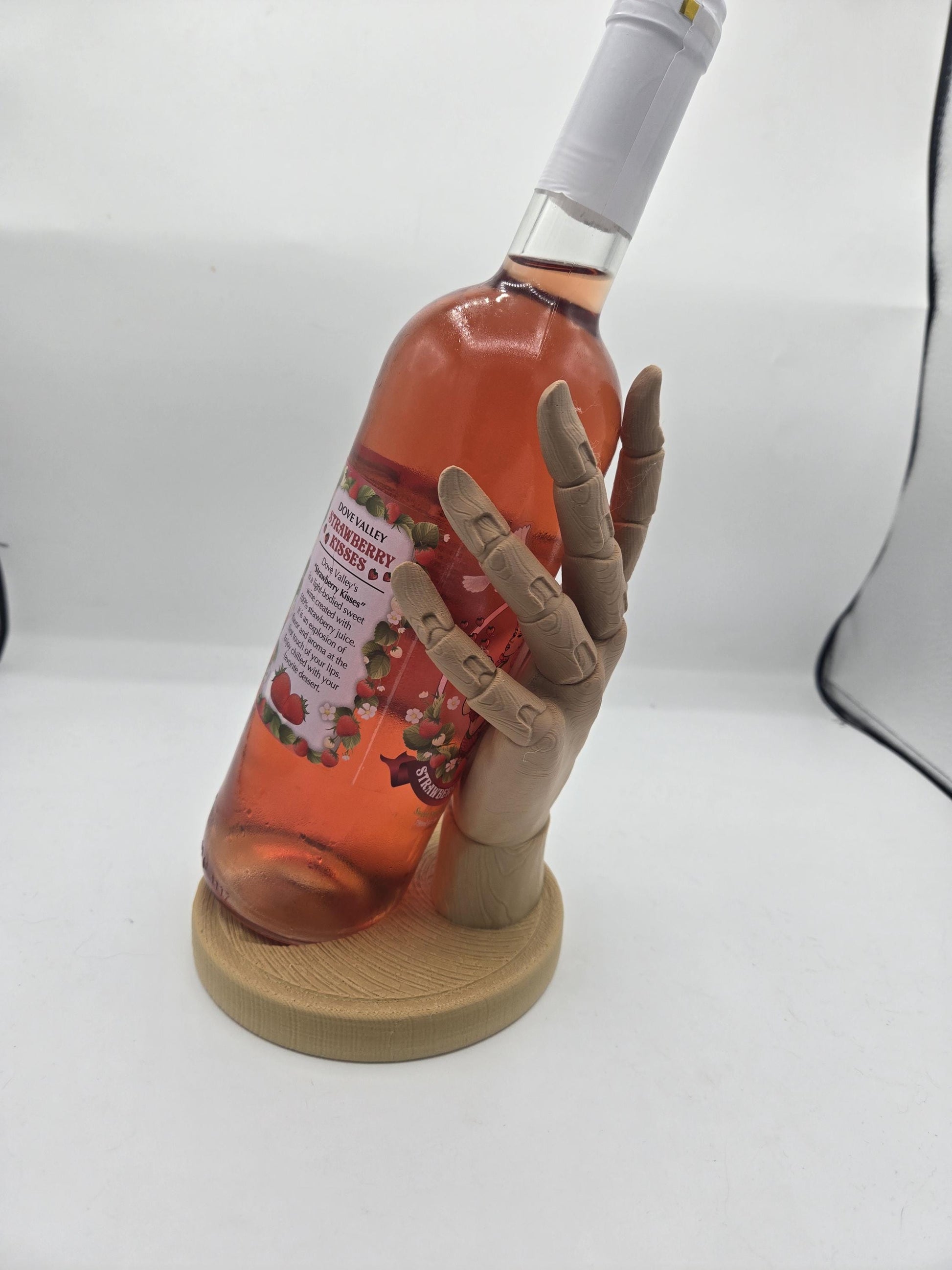 Wooden hand holder displaying a wine bottle at an angle — fingers wrapping the bottle for a floating held look