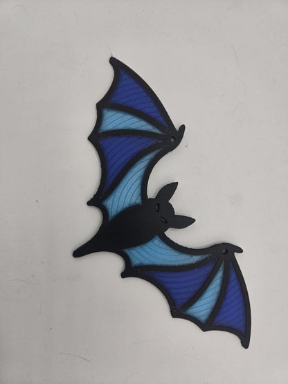3D printed bat window hanging with black frame and layered blue translucent wing panels, full view on white background