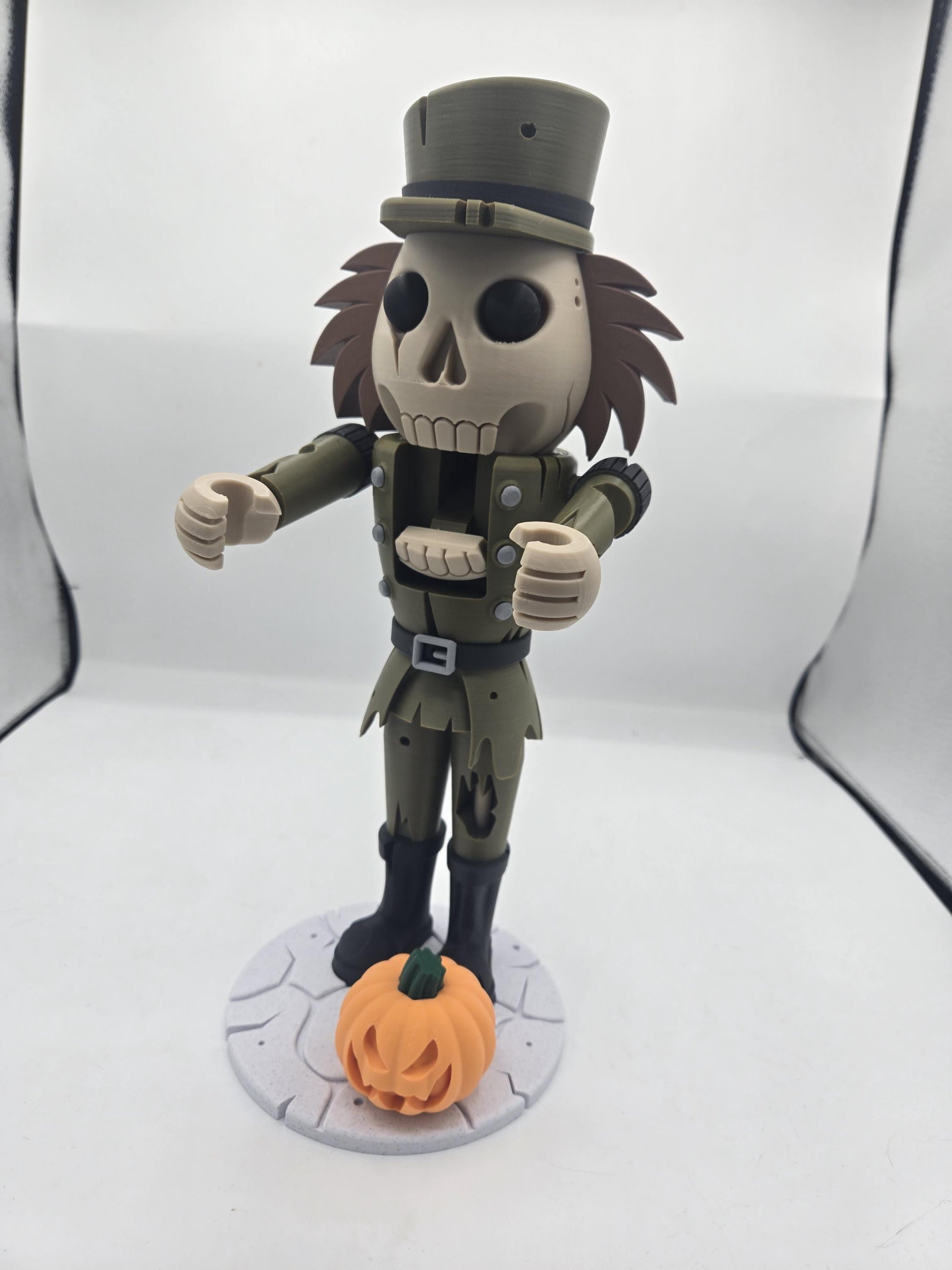 Halloween spooky nutcracker figure — skull face, tall olive hat, tattered uniform, and jack-o'-lantern pumpkin at its boots, 3D printed