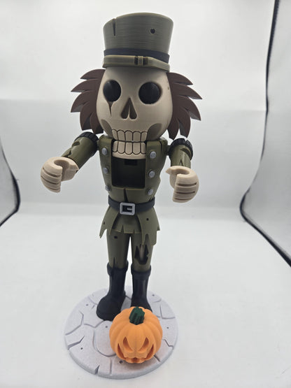 Front view of the skeleton nutcracker display decoration standing on a stone-look base with a mini pumpkin
