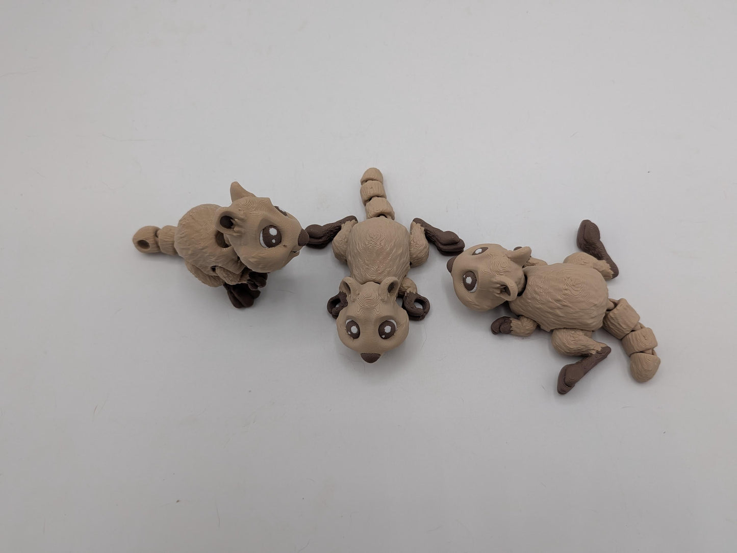 Top view of three articulated mini quokka figurines with keychain tail loop visible on the left one