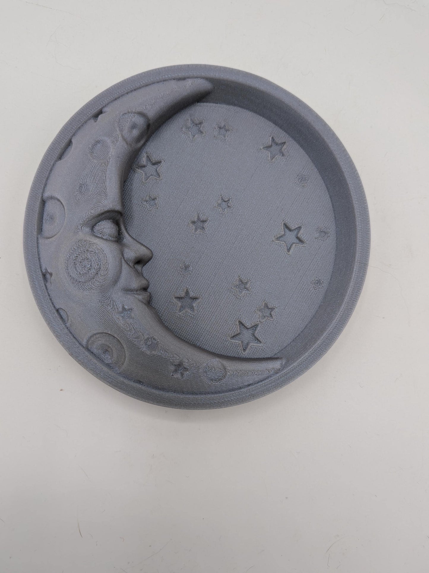 Angled top view of the celestial moon and star trinket tray showing sculpted moon face, scattered stars, and raised rim