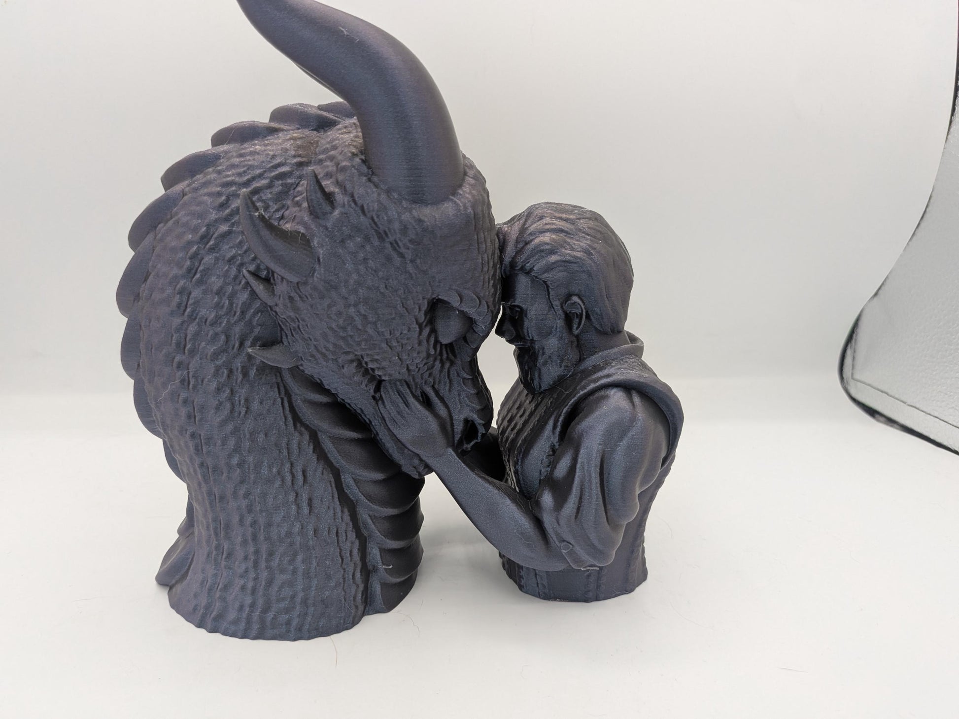 Male rider version of the dragon bonding statue in dark silk filament, hands cradling the dragon's jaw