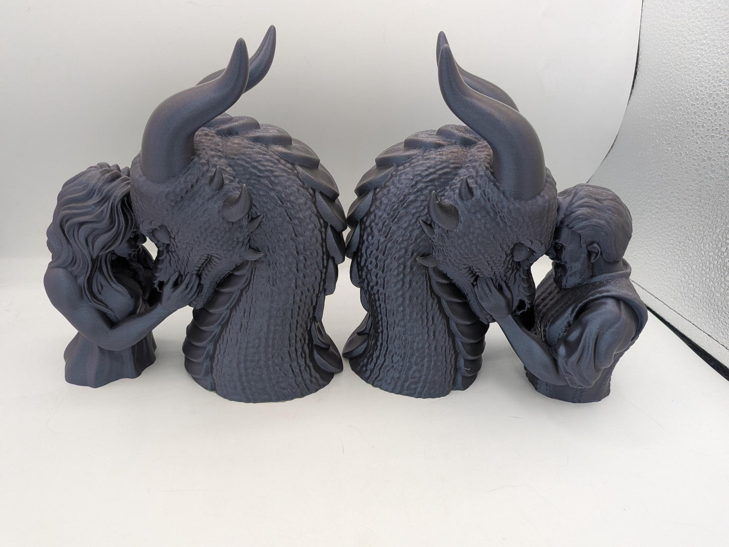 Two dragon rider bonding statues shown as a bookend pair, female rider and male rider versions back to back