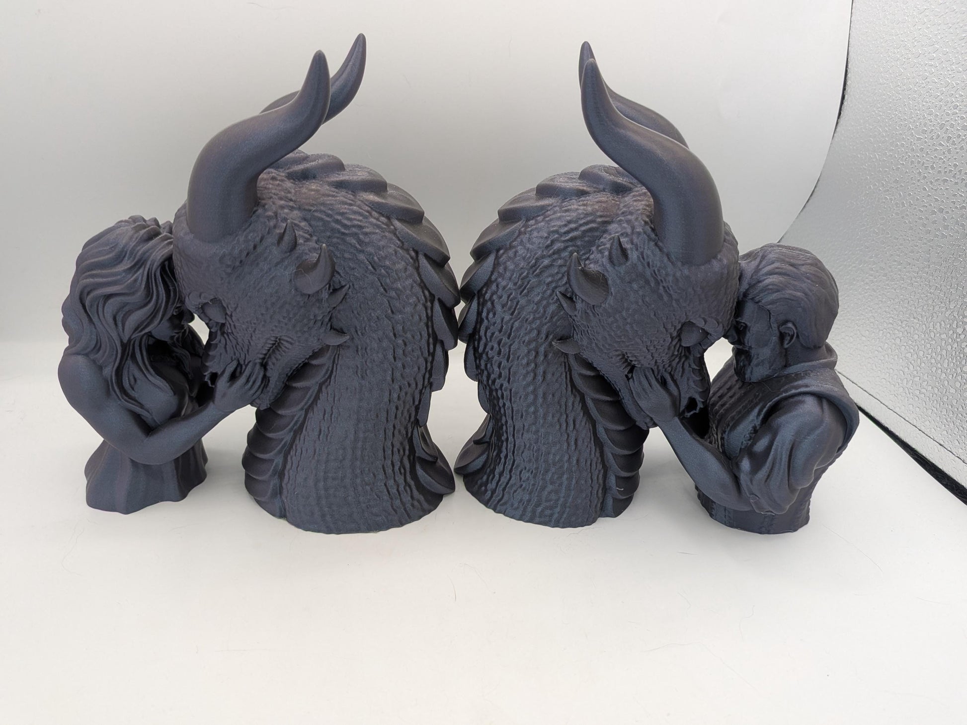 Two dragon rider bonding statues shown as a bookend pair, female rider and male rider versions back to back