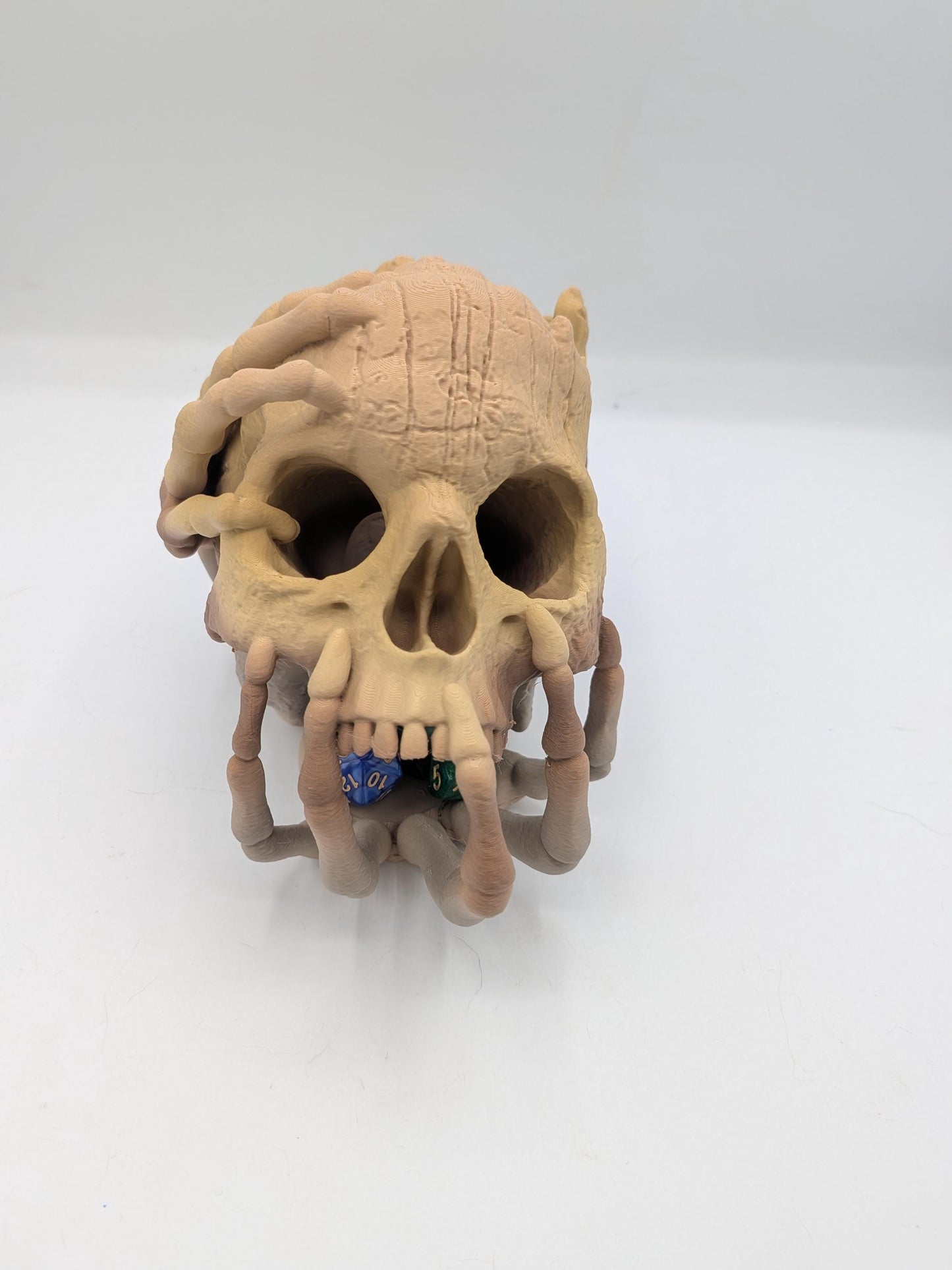 Front view of the gothic skull dice tower with skeletal fingers framing the face and dice under the teeth