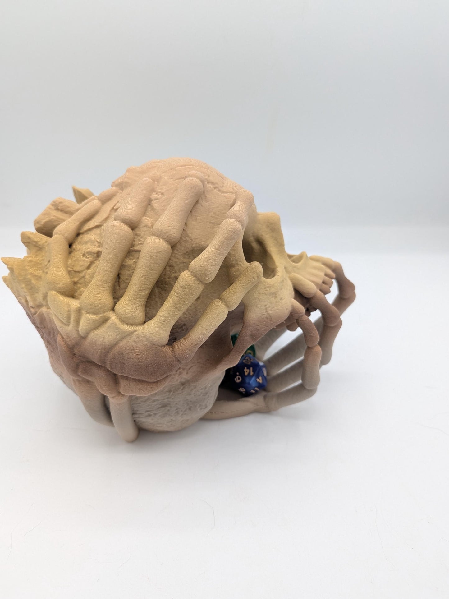 Side view of the skeletal hand wrapped skull dice tower with dice rolled out into the waiting bone hand