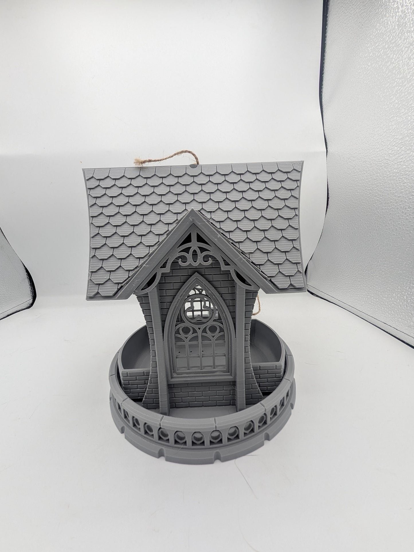 Straight-on view of the gothic church bird feeder — arched window, brick and balustrade detail