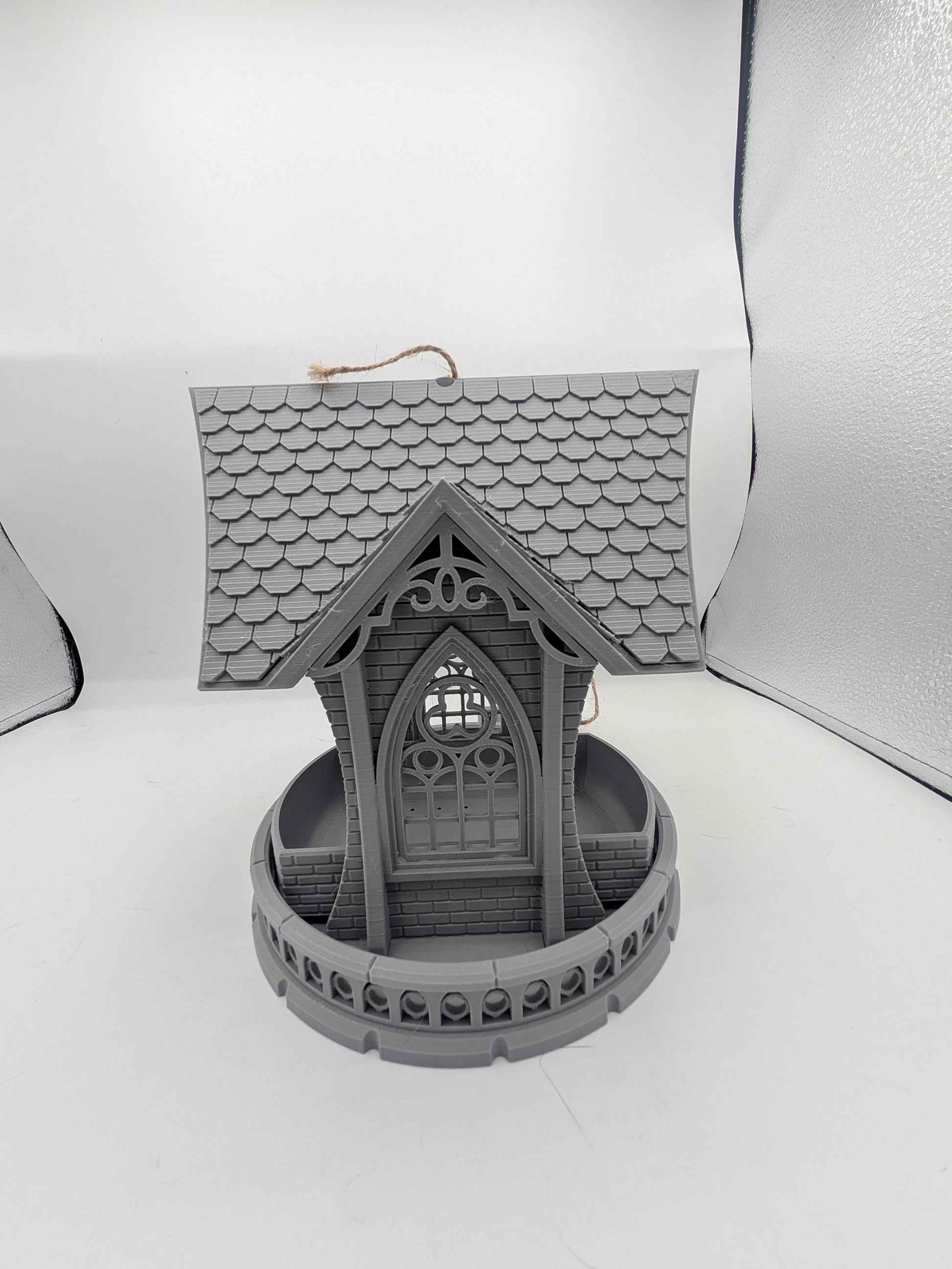 Straight-on view of the gothic church bird feeder — arched window, brick and balustrade detail