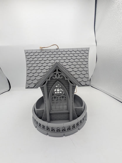 Straight-on view of the gothic church bird feeder — arched window, brick and balustrade detail
