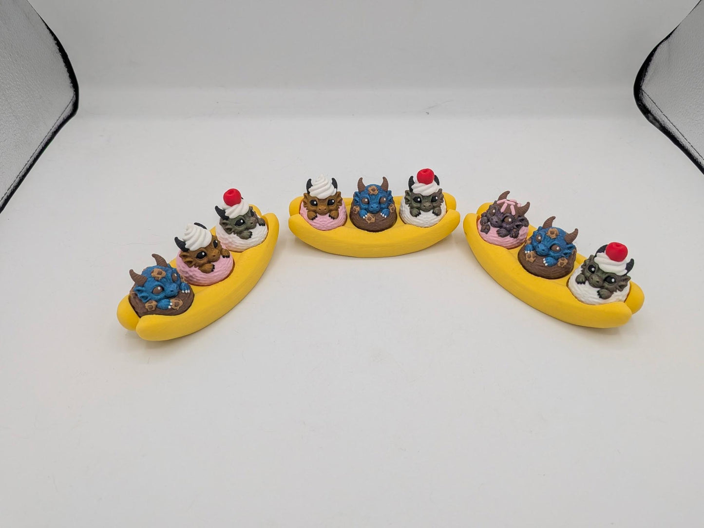 Dragon banana split fidgets lined up showing the three dragon ice cream scoops on each banana base