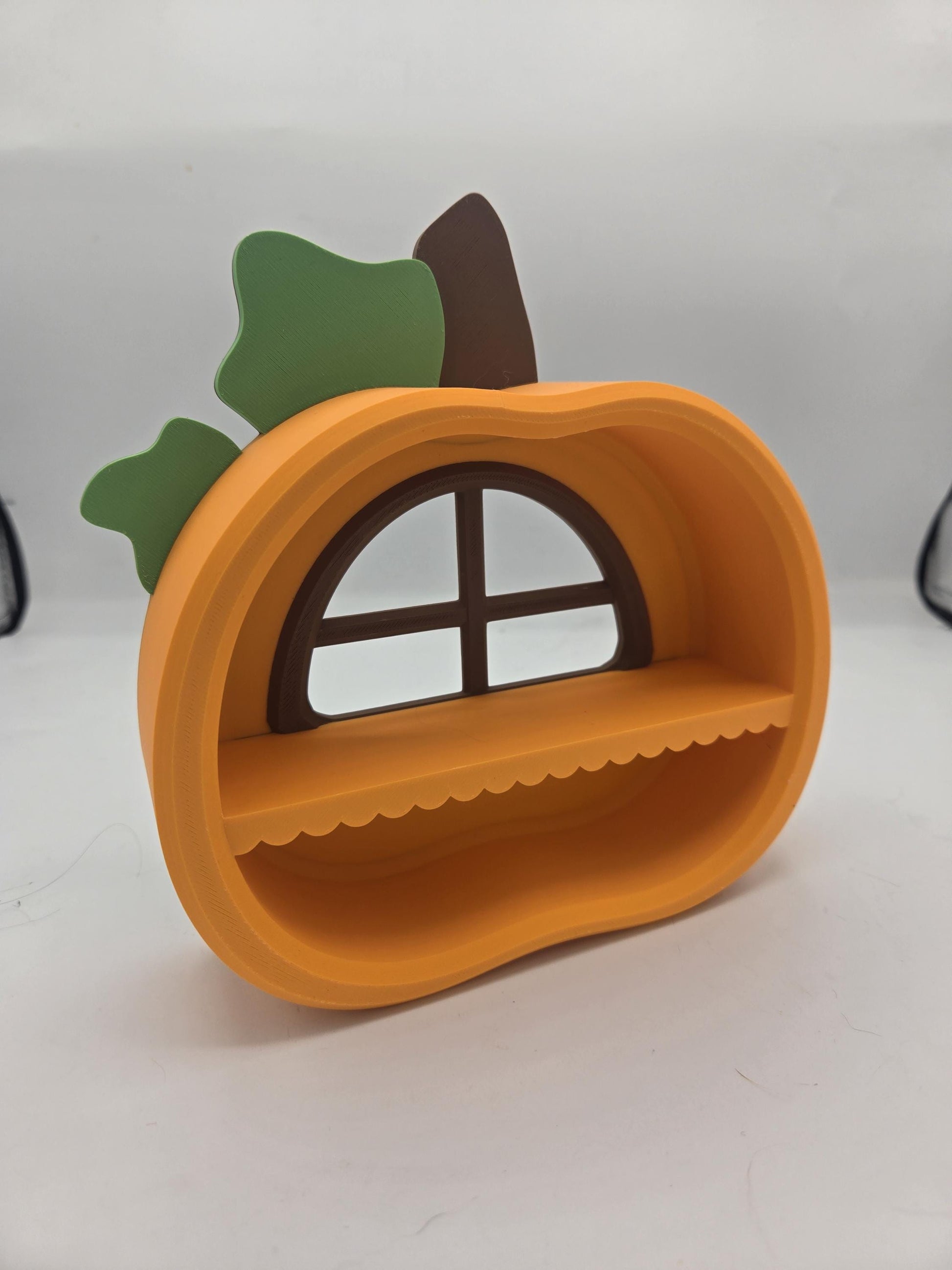 Pumpkin Trinket Shelf angled view — 3D printed orange pumpkin with green leaves, brown stem, window-style back, and scalloped display shelf
