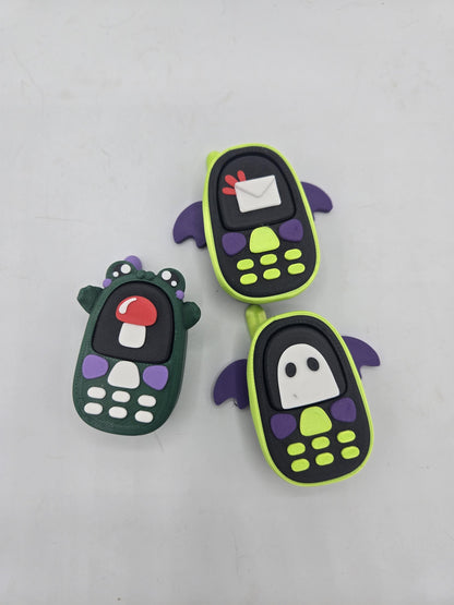 All three kawaii phone clicker styles together — frog with mushroom screen, bat with envelope screen, and bat with ghost screen, 3D printed