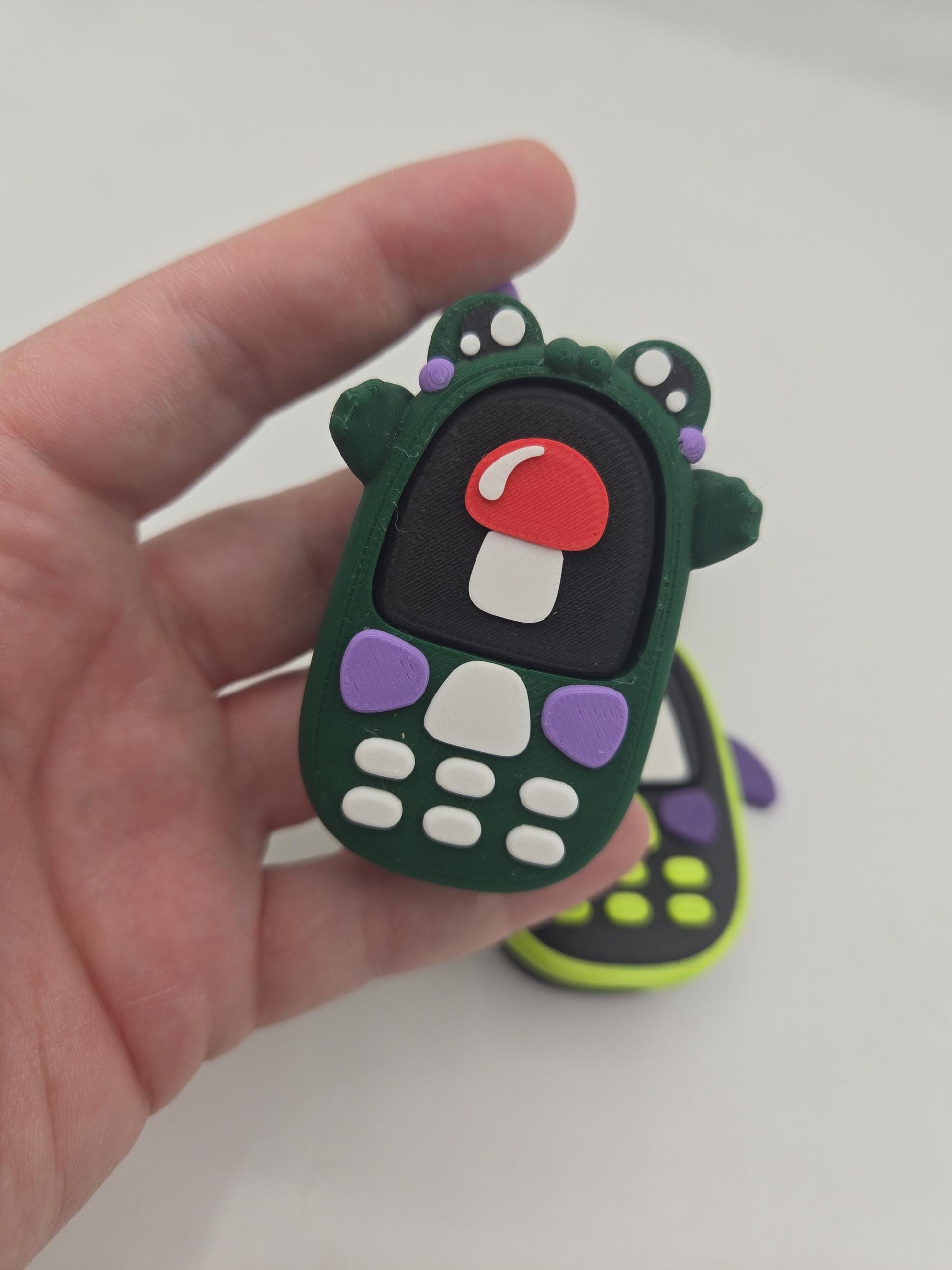 Kawaii frog phone clicker with mushroom screen held in hand — palm-sized 3D printed fidget with built-in mechanical key switch