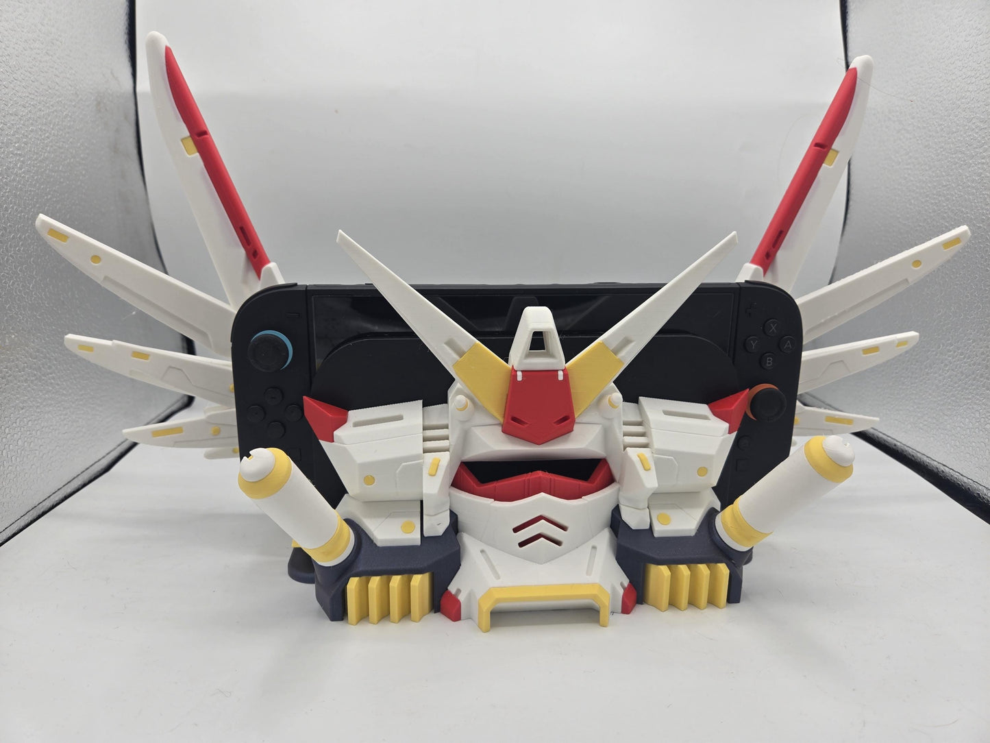 Mechdam Nintendo Switch 2 Dock Display, 3D printed — white, red, and yellow mecha head with raised wing array framing the docked console