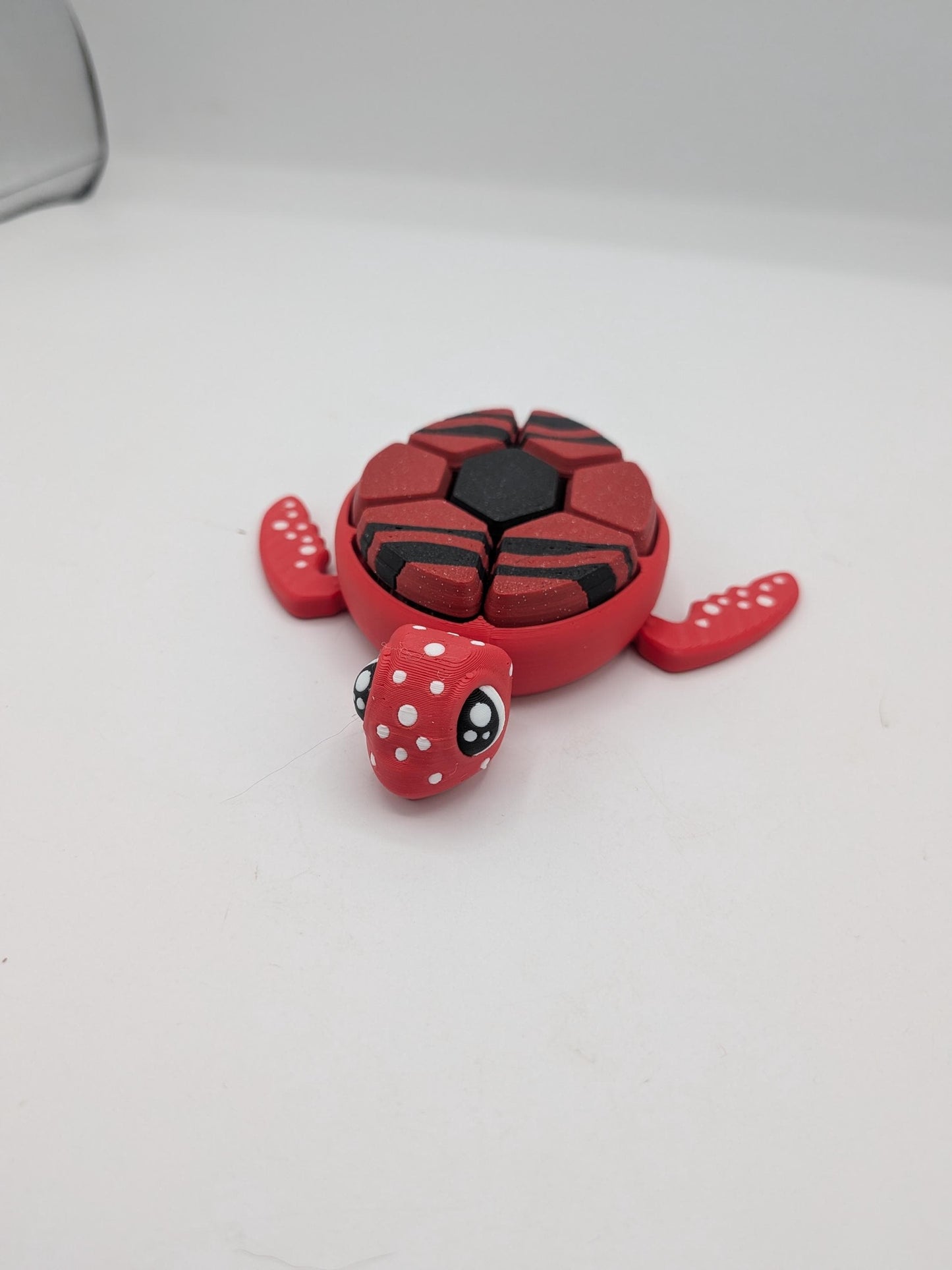 Front view of red turtle clicker fidget with white spotted face and striped shell clicker keys