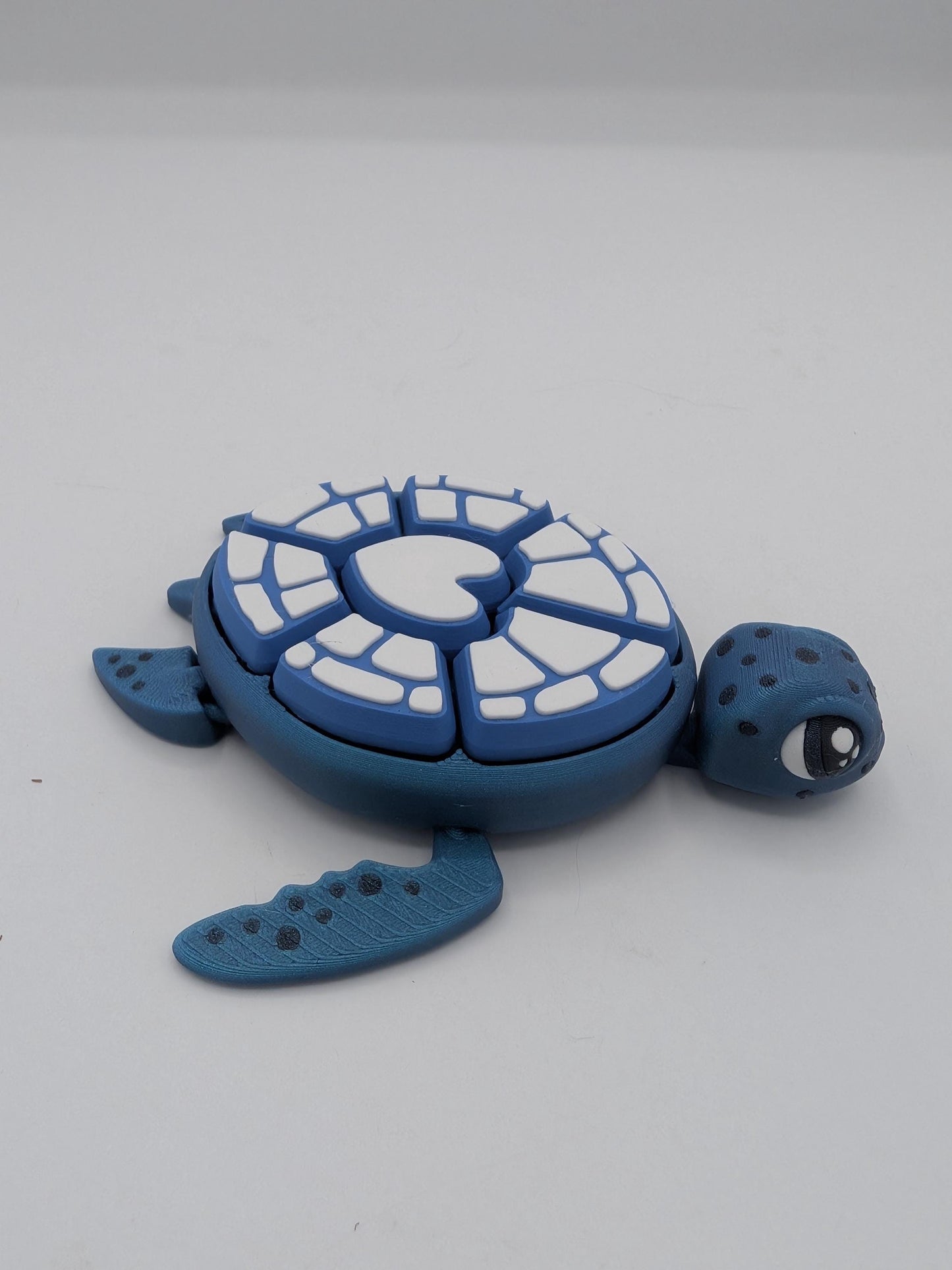 Blue turtle mechanical clicker fidget side view showing white heart design shell and articulated flippers