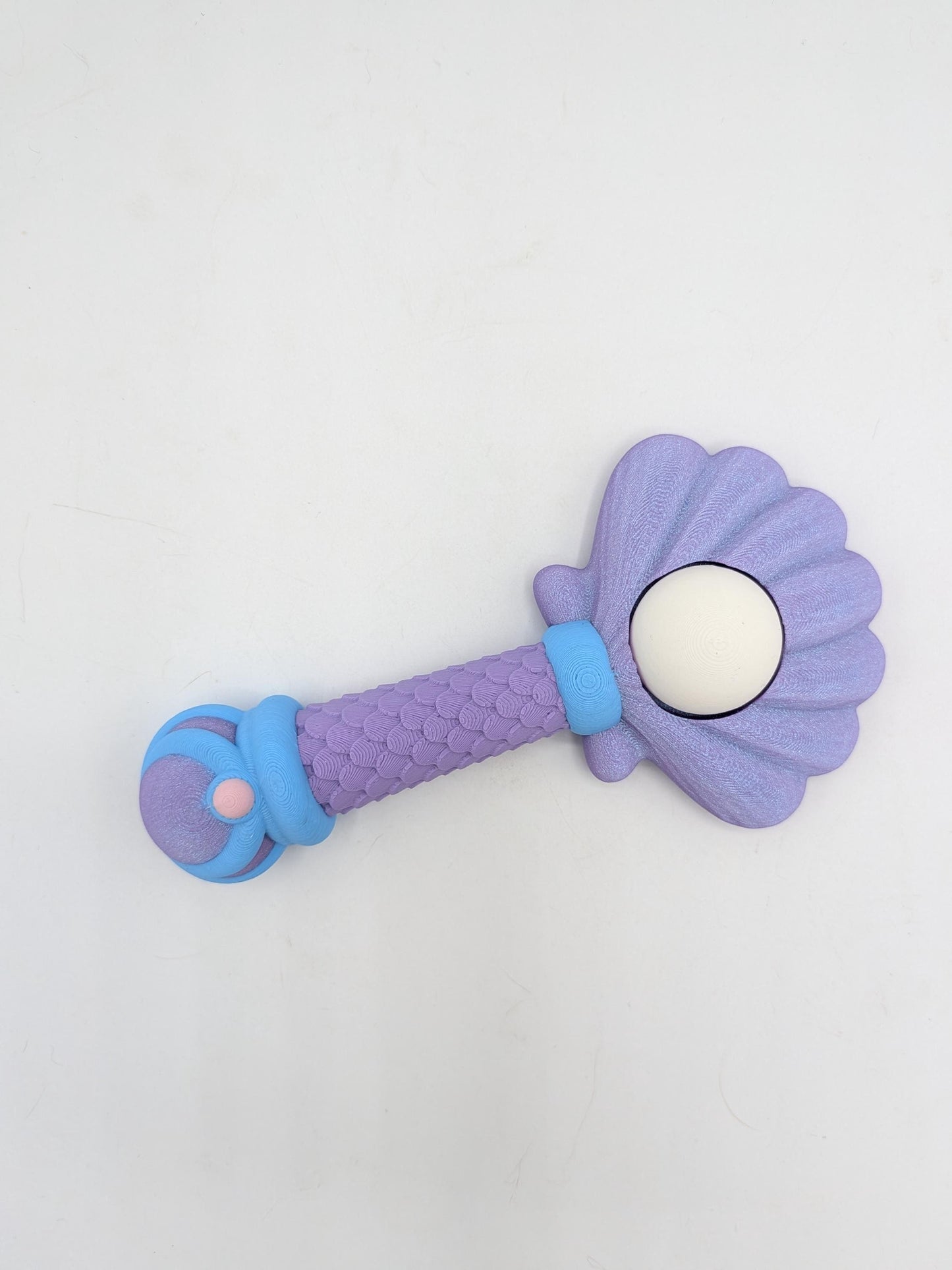 Mermaid wand clicker fidget lying flat showing shell-shaped top, pearl detail, and blue accent bands