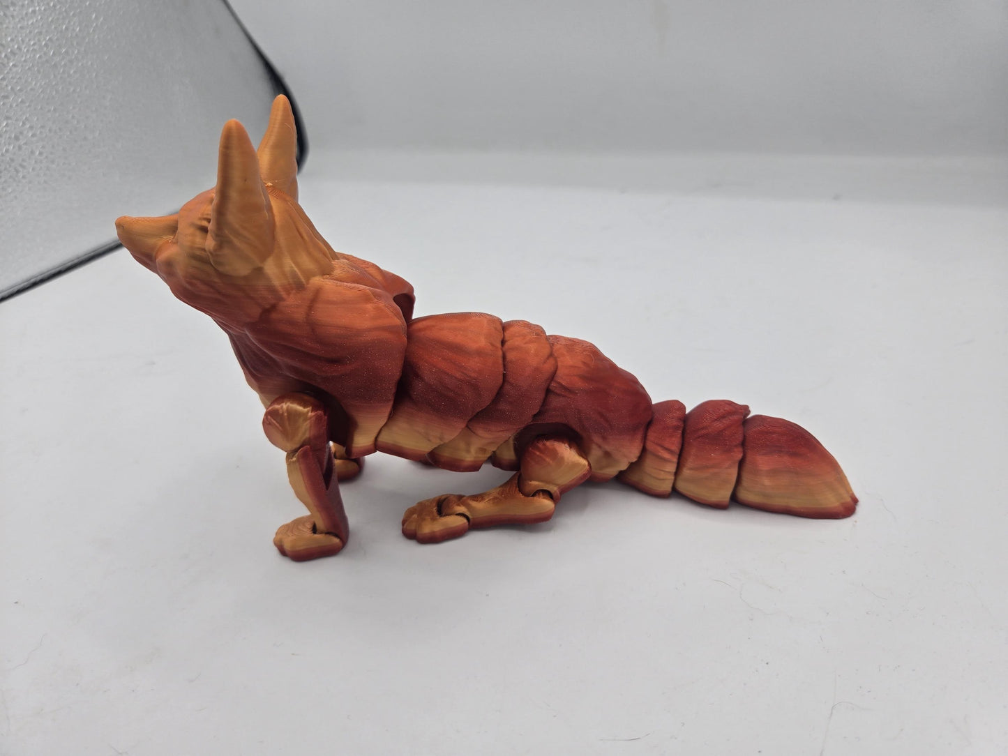 Side profile of fennec fox flexi figurine in red-gold gradient with articulated legs and tail
