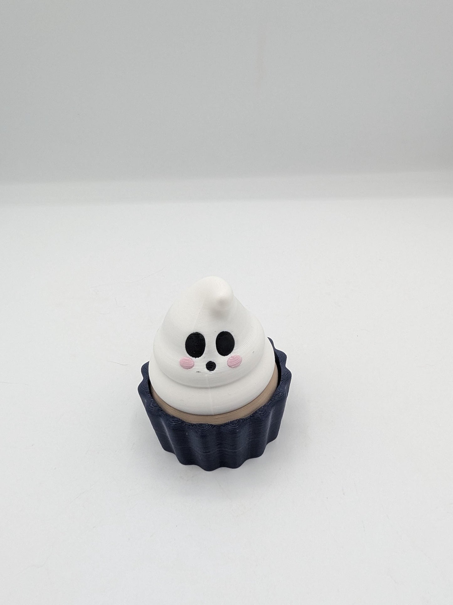 Ghost Halloween cupcake clicker fidget with white ghost frosting swirl face in a dark navy tin